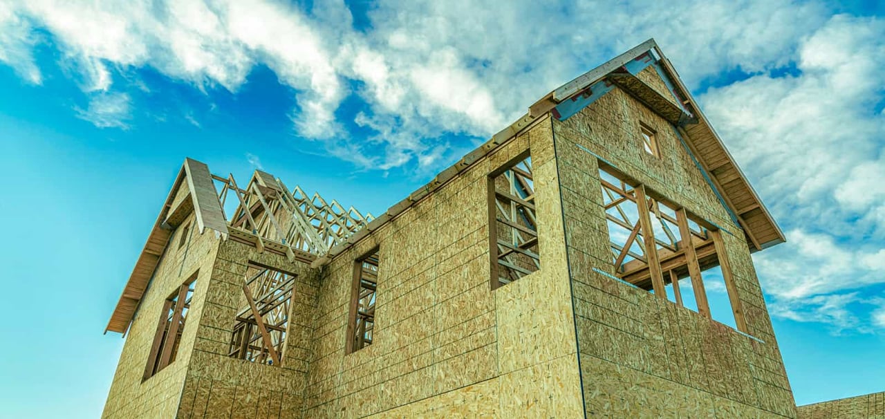 A view from below a partially constructed home looking up at a cloudy sky.